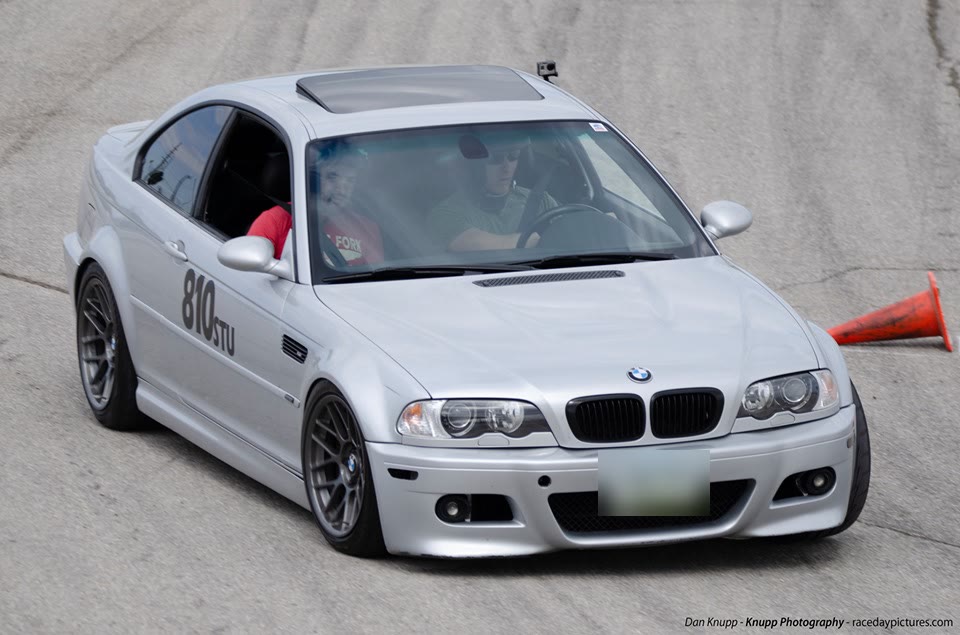 The silver E46 M3, number 810, on an autocross course with two people inside and a cone beside it