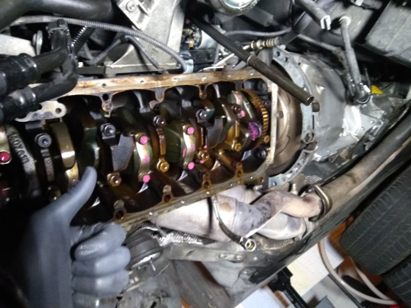 The underside of the M3's engine with the oil pan removed, showing the crankshaft and paint-marked connecting rod bolts