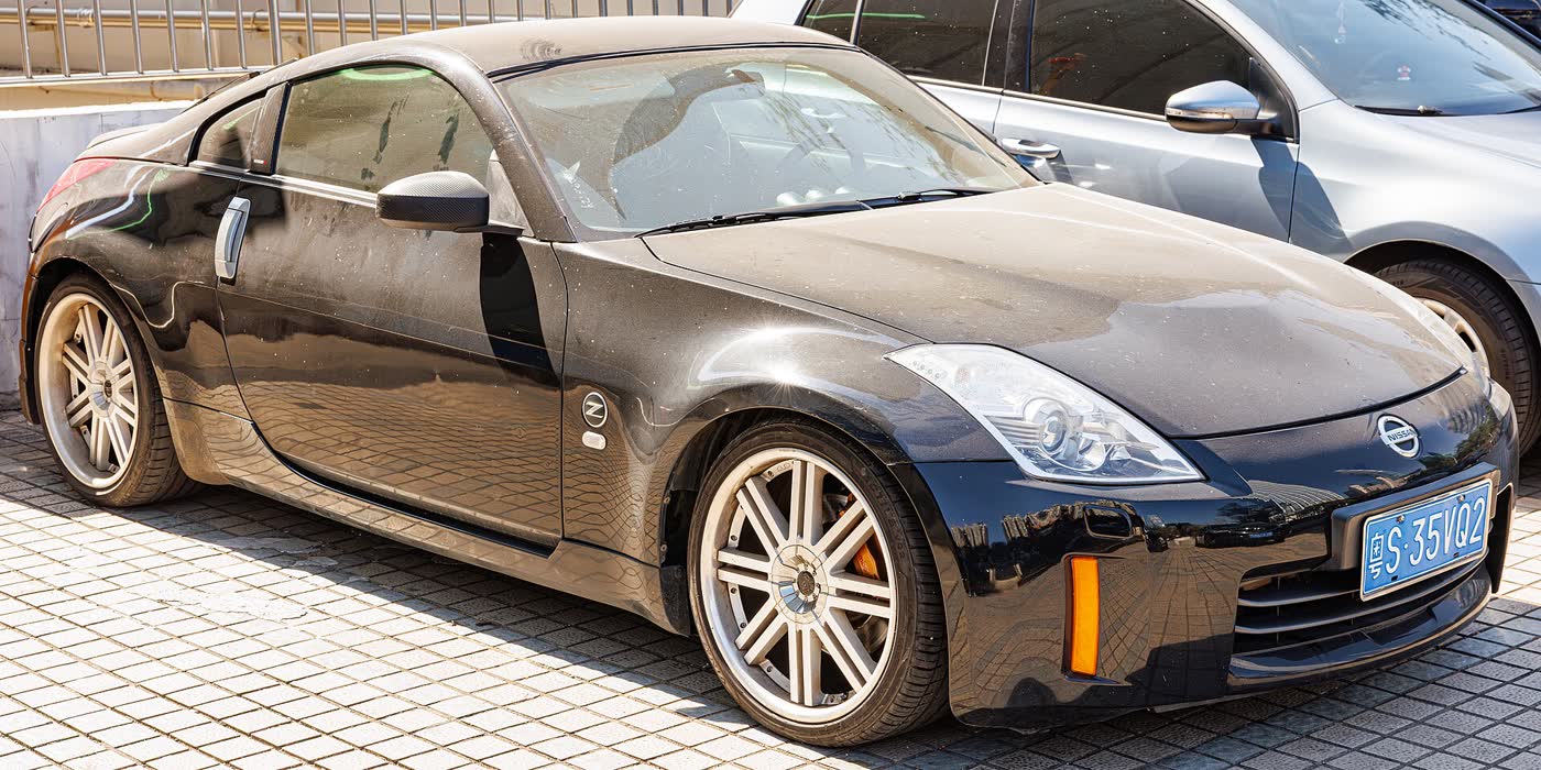 A black Nissan 350Z coupe on a street, front three-quarter view with polished alloy wheels