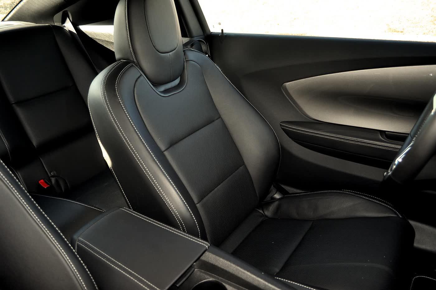 The black leather seats of a 2013 Chevrolet Camaro, showing the front seat and the rear bench behind it