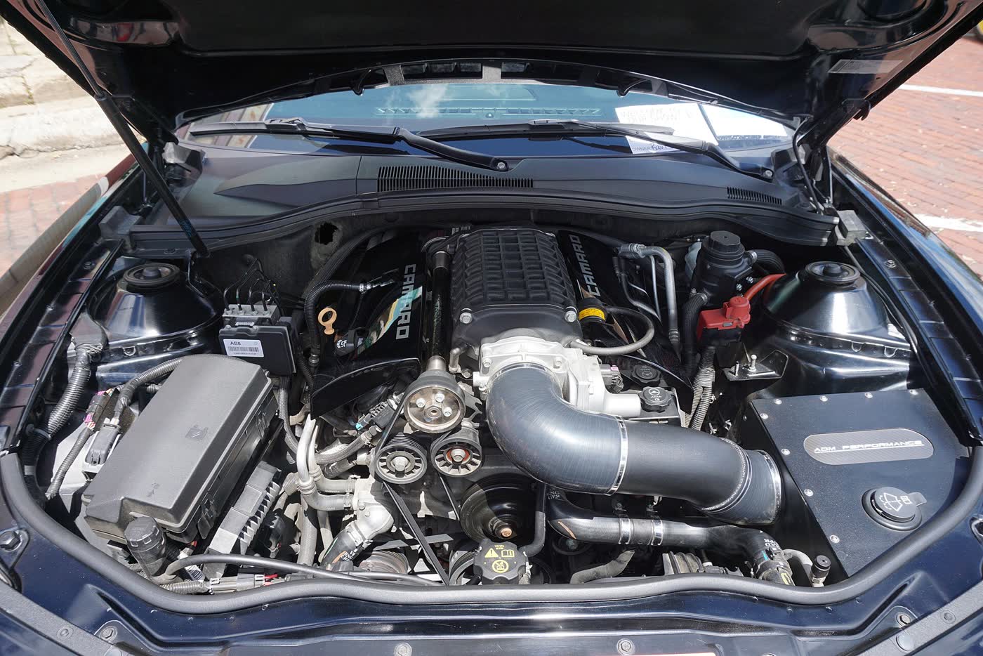 The engine bay of a fifth-generation Chevrolet Camaro fitted with a supercharger and an aftermarket intake