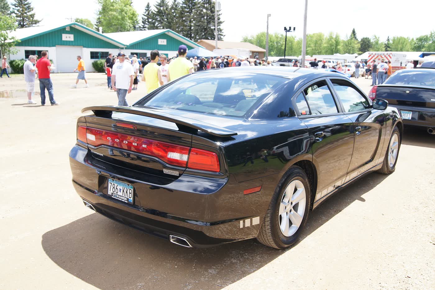 A black 2012 Dodge Charger R/T seen from the rear three-quarter, showing the full-width tail lamp and twin exhaust tips