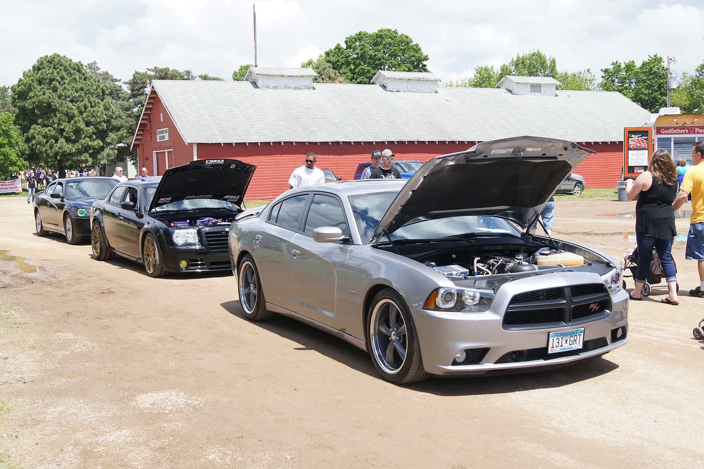 A silver 2011 Dodge Charger R/T with its hood raised at a car show, R/T badge visible on the grille
