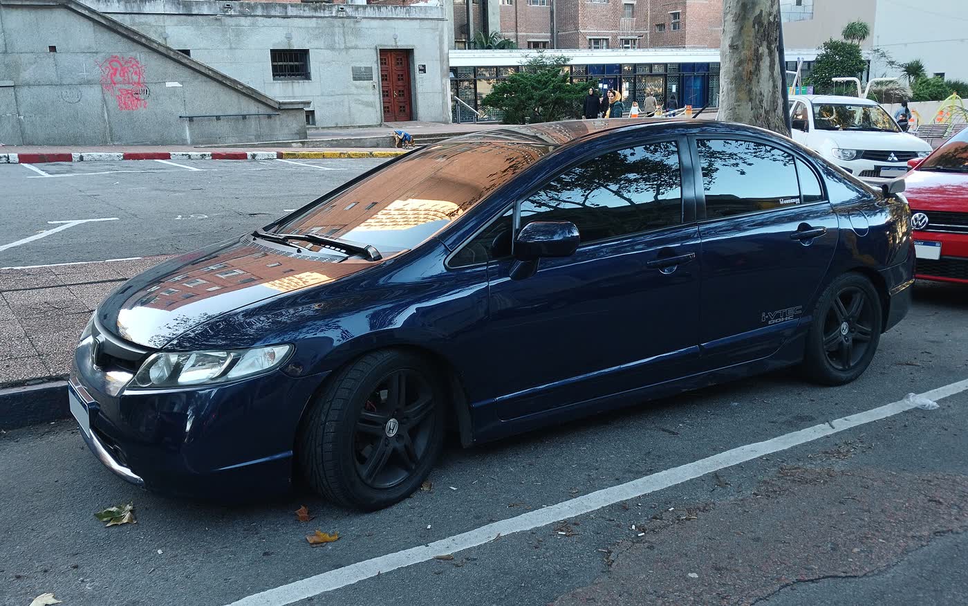 A modified eighth-generation Honda Civic sedan on a street, lowered on black aftermarket wheels