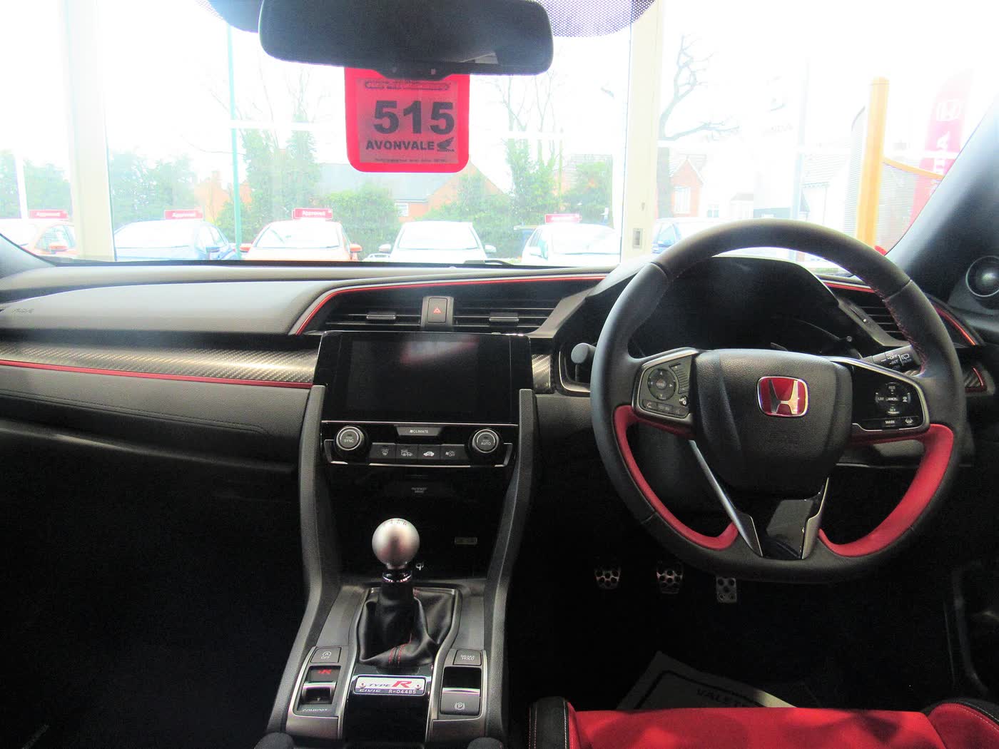 The interior of a Honda Civic Type R FK8, showing the red bucket seats and the aluminium shifter