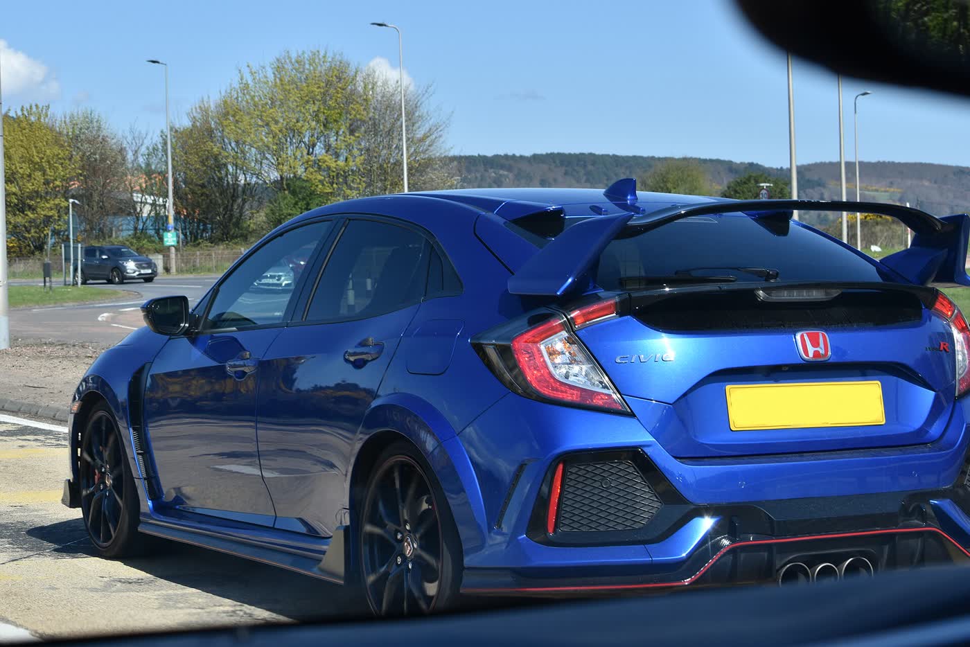 A Honda Civic Type R FK8 with its rear wing and triple exhaust, three-quarter view
