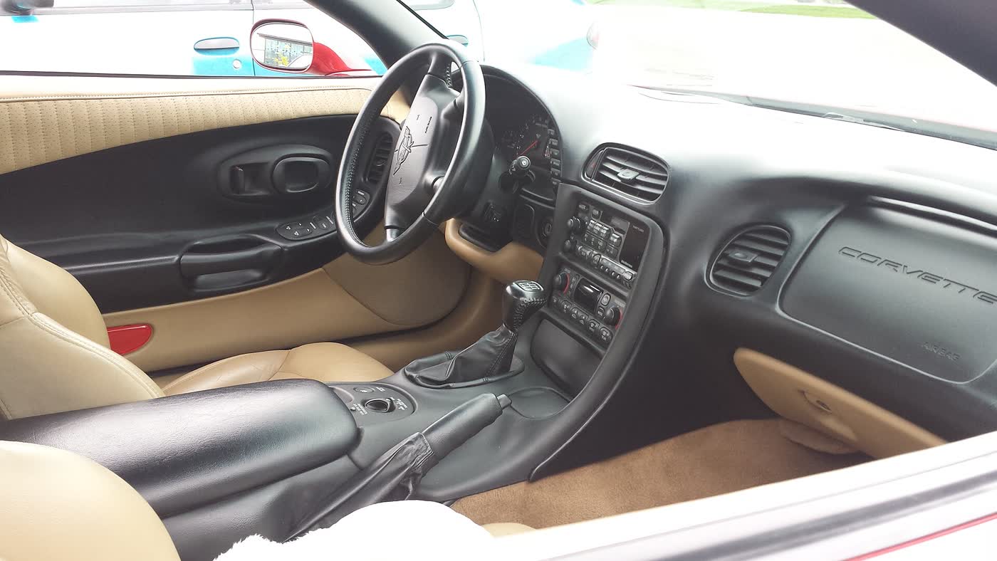 The interior of a Chevrolet Corvette C5 with a tan and black cabin and a six-speed manual shifter