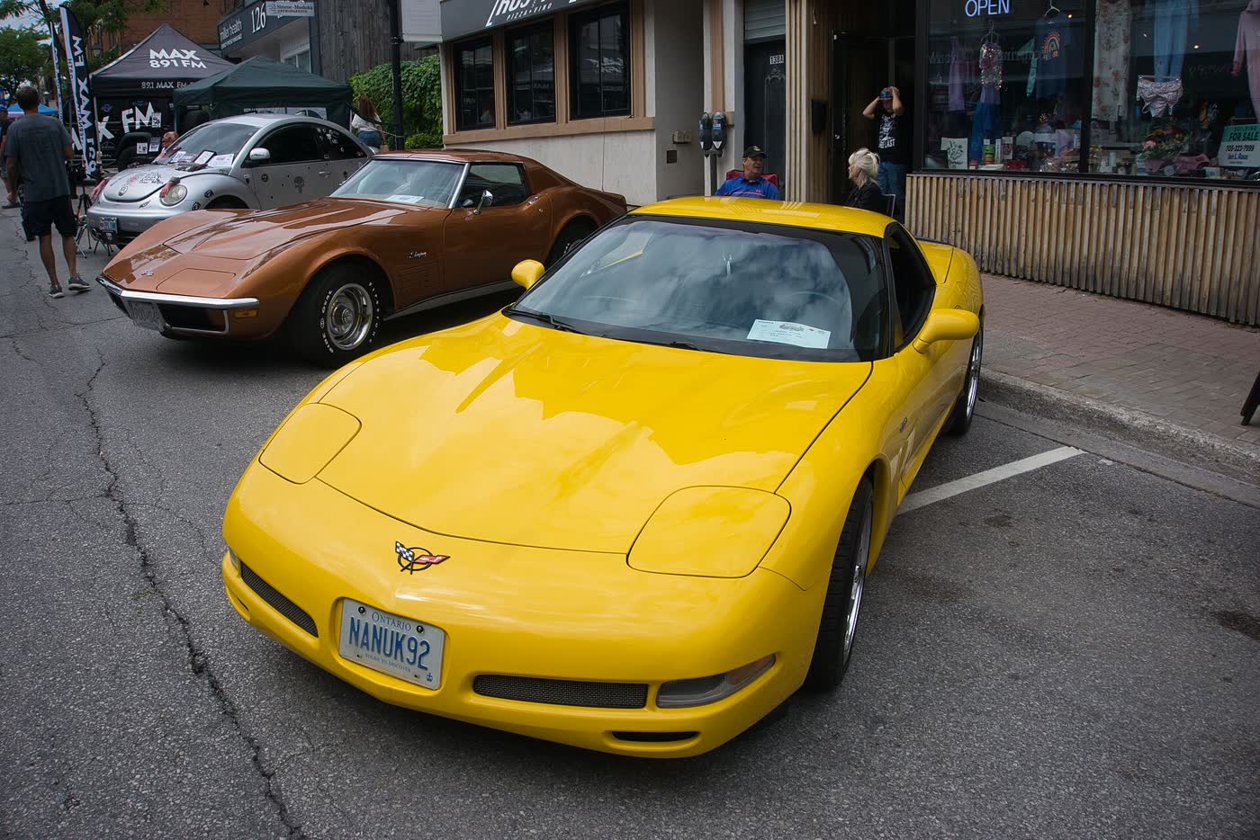 A yellow Chevrolet Corvette C5 coupe parked on a street at a car show, front three-quarter view
