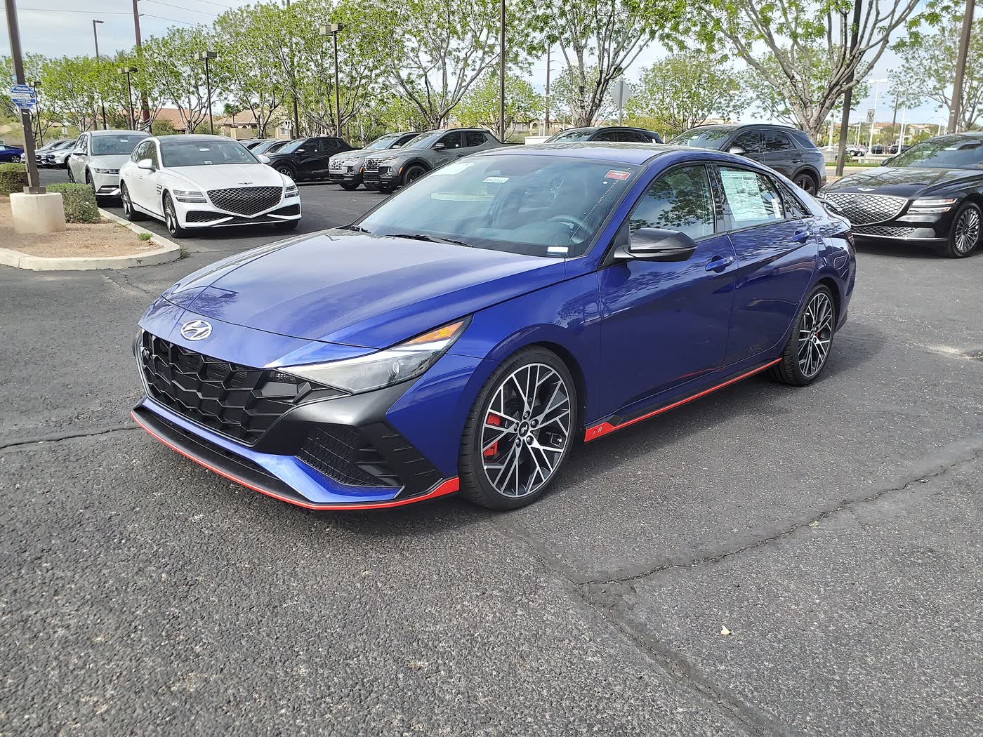 A blue 2023 Hyundai Elantra N sedan with red lower trim, front three-quarter view, parked on a dealer lot