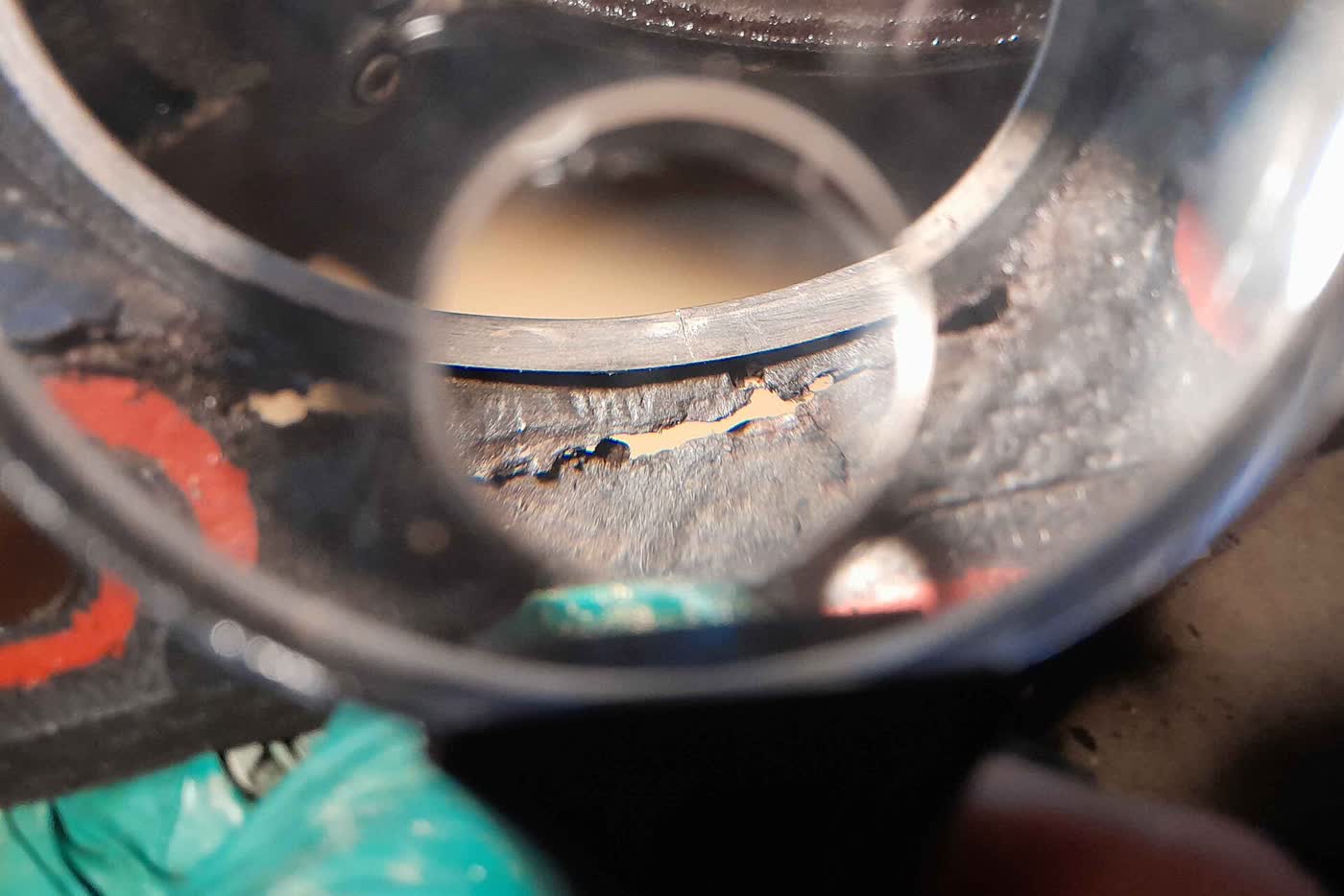 A close-up through a magnifier of a split head gasket, with coolant contamination visible
