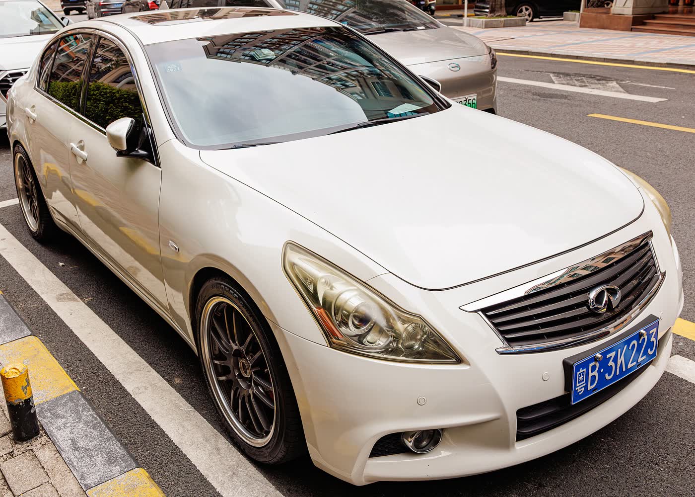 A white Infiniti G37 sedan parked at a kerb, front three-quarter view