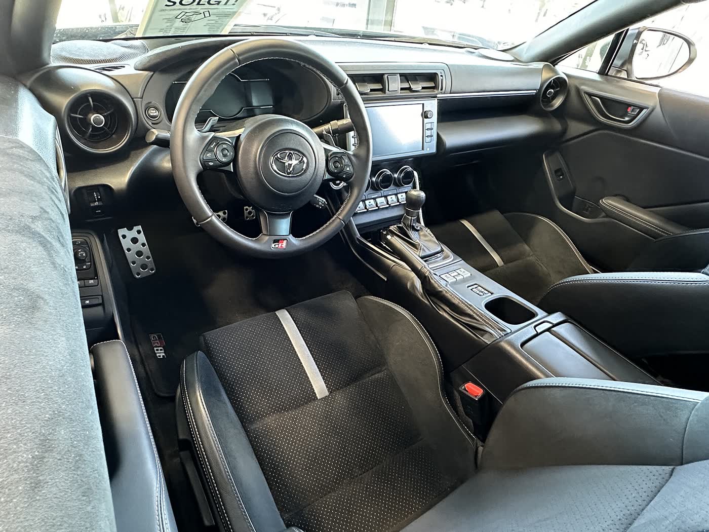 The interior of a Toyota GR86, showing the dashboard, gauges and manual shifter