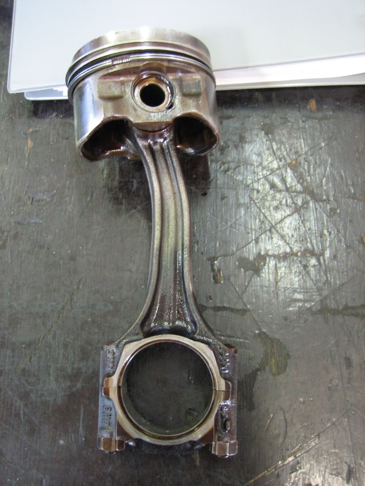A piston and connecting rod removed from an engine, the rod visibly bent and the big-end bearing shells exposed