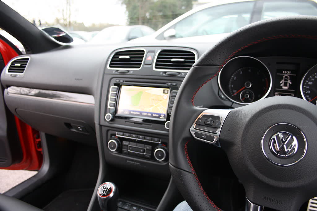 The interior of a Mk6 Volkswagen Golf GTI, showing the flat-bottomed wheel, nav screen and golf-ball shifter