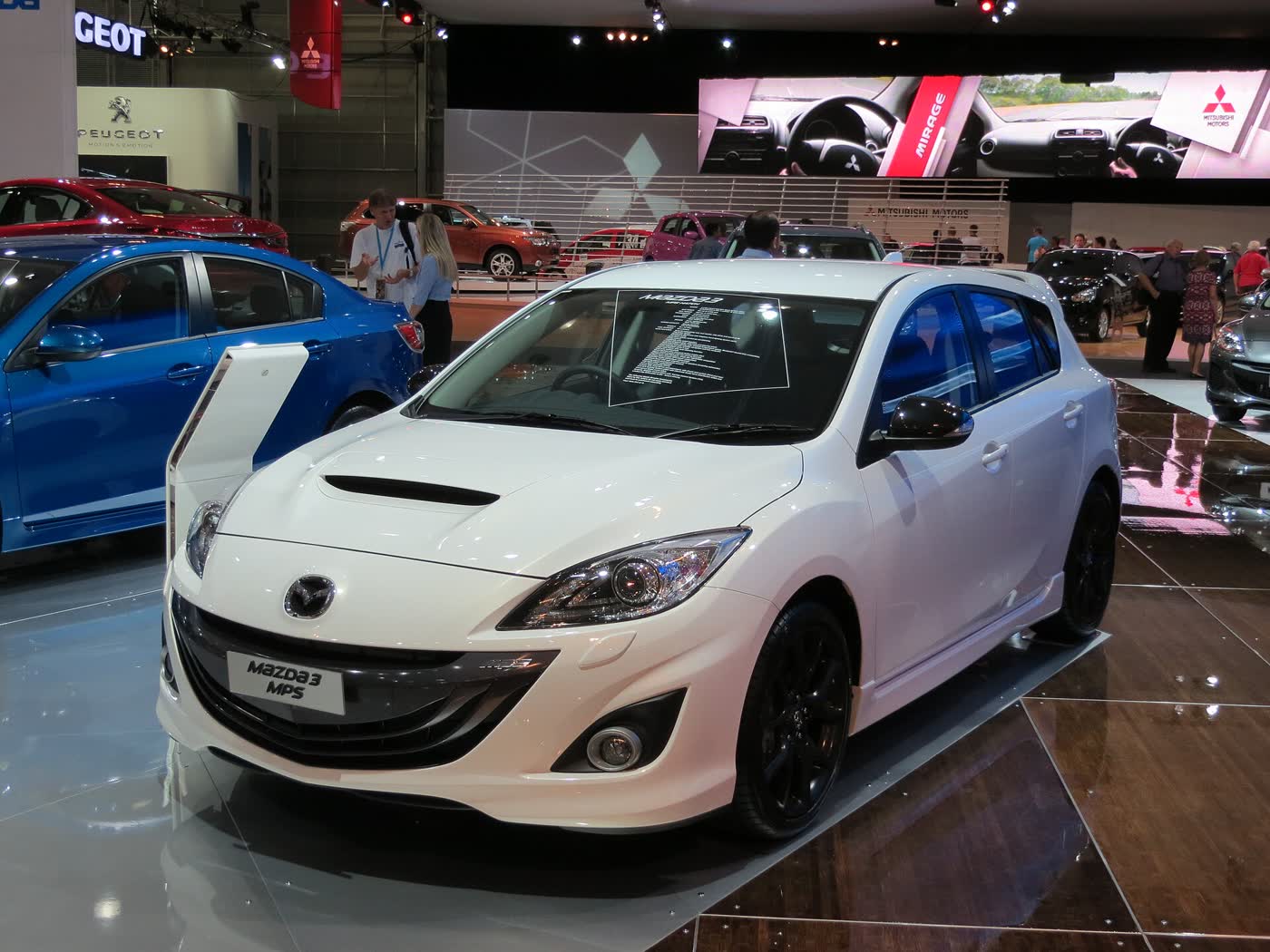 A white 2012 Mazda3 MPS hatchback on a motor show stand