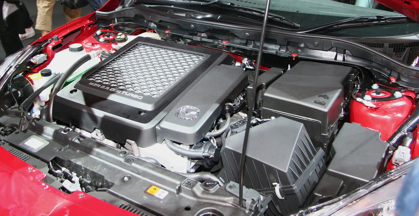 The engine bay of a Mazdaspeed3, the cover reading MZR 2.3 DiSi Turbo