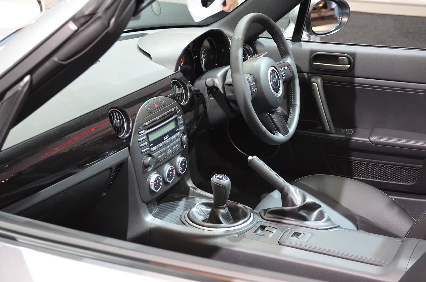 The cabin of a Mazda MX-5 NC, showing the six-speed shifter, handbrake and centre stack