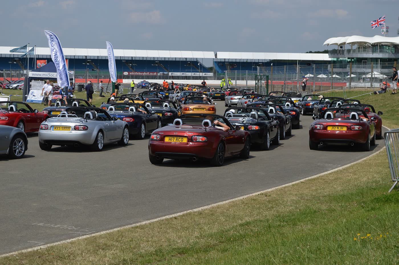 A pack of Mazda MX-5 race cars running close together on a circuit at Silverstone