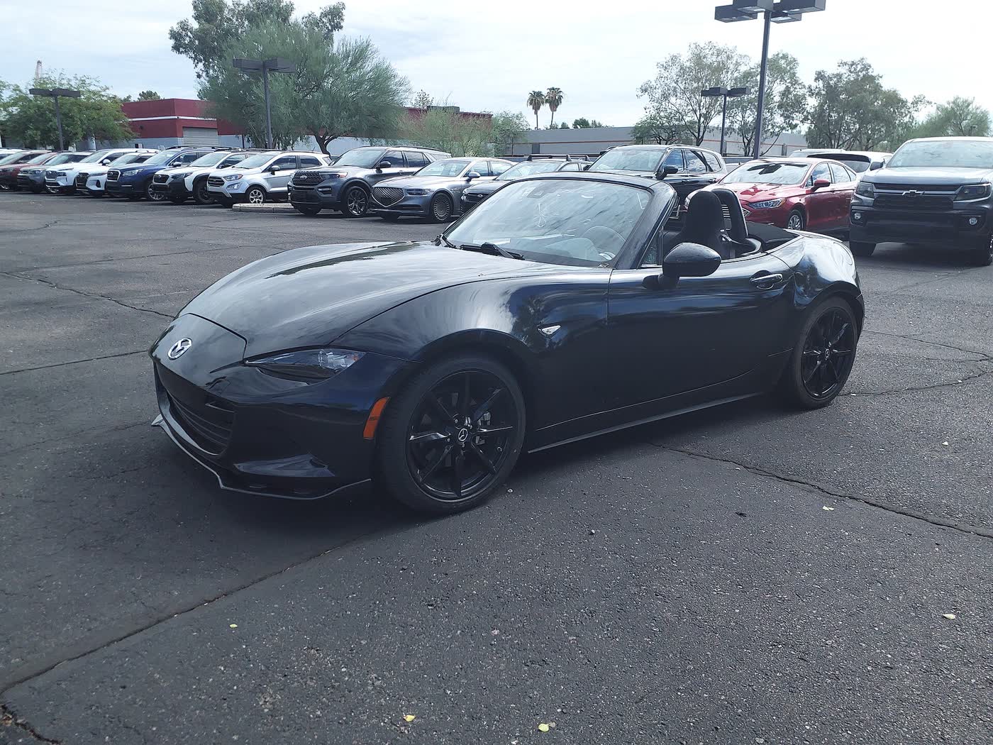 A black 2020 Mazda MX-5 Miata Club soft-top, top down, parked on a dealer lot