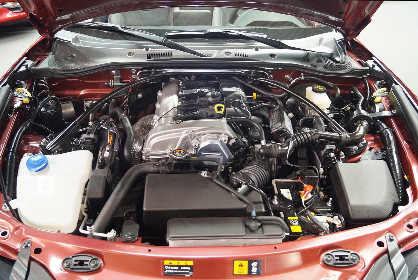 The engine bay of a Mazda MX-5 ND, showing the 2.0 Skyactiv-G, airbox, coolant tank and strut towers