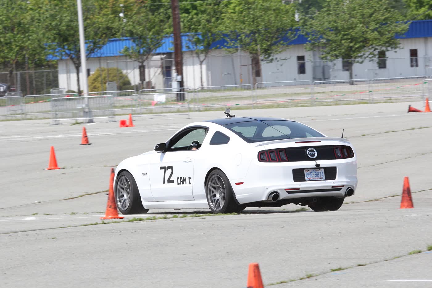 A white Ford Mustang GT cornering on an autocross course with a class number on the door and cones laid out around it