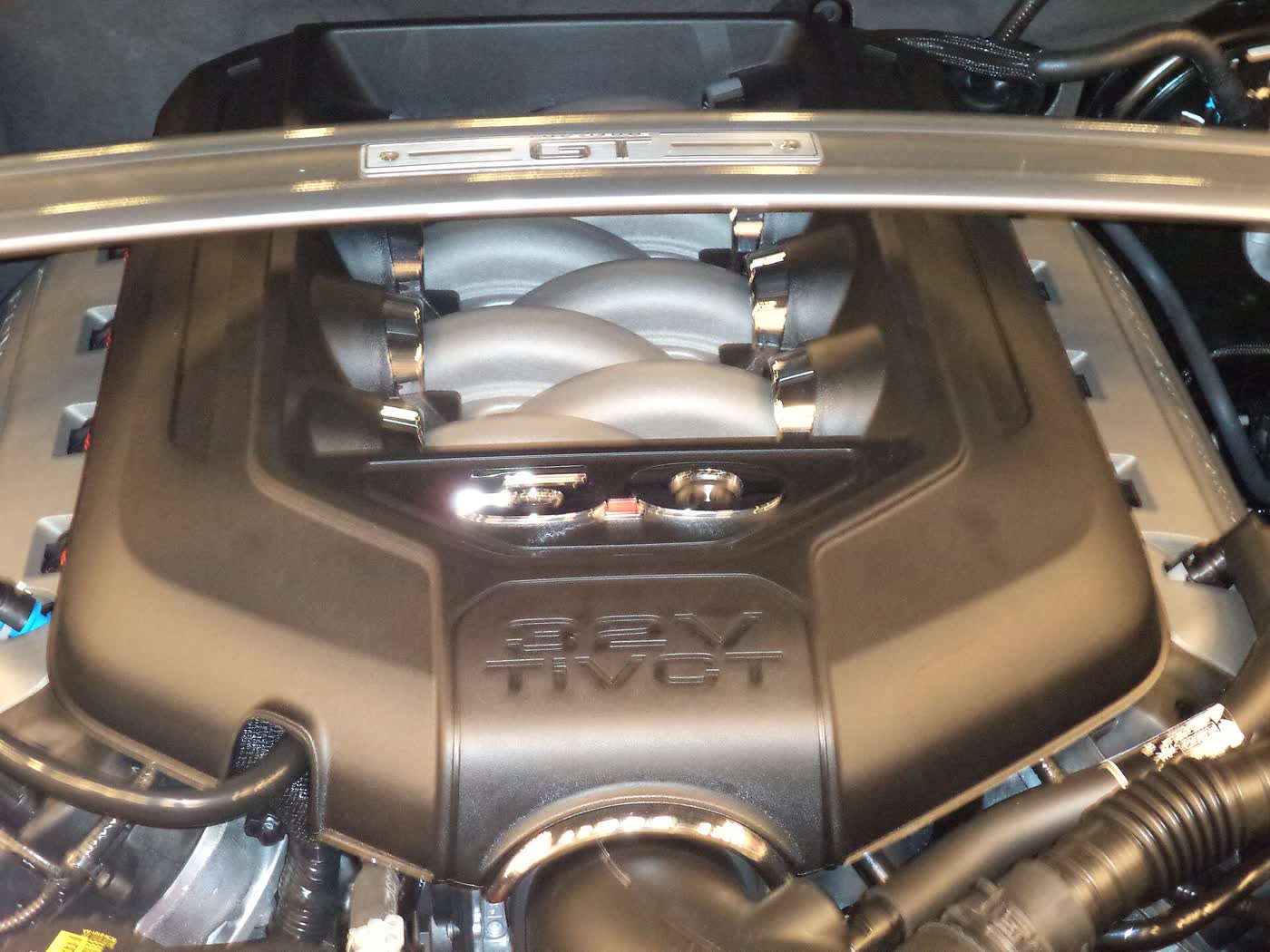 The Coyote 5.0 V8 in a Mustang engine bay, its 32-valve TiVCT cover and GT strut brace visible