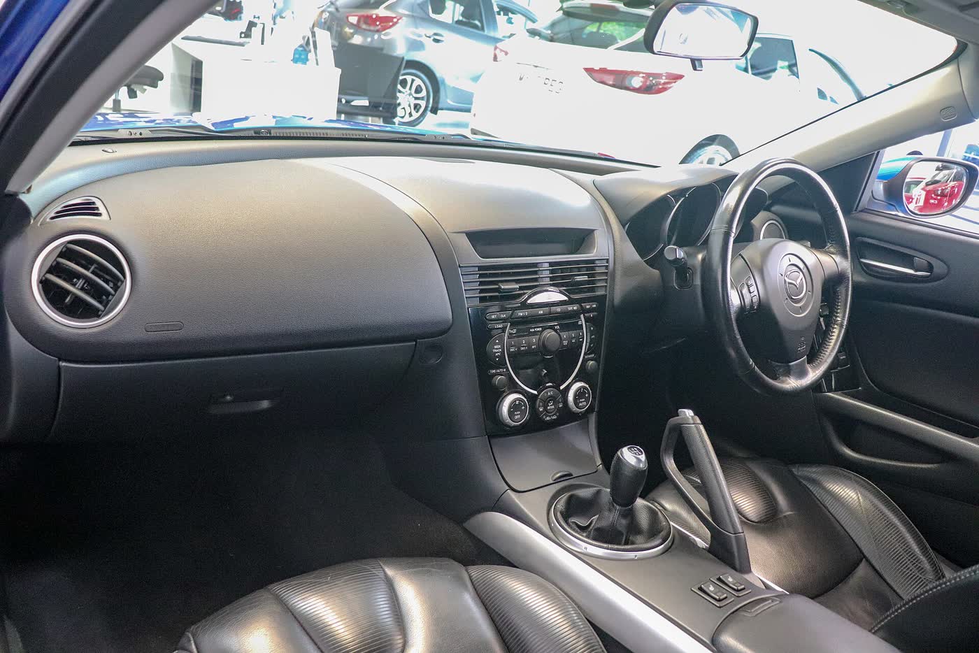 The interior of a Mazda RX-8 showing the driver's seat, wheel and the rear-hinged back doors