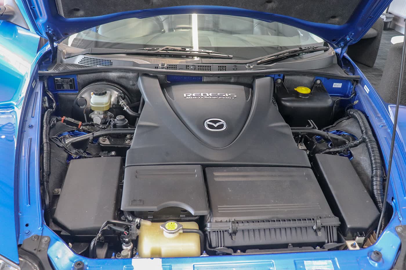 The engine bay of a Mazda RX-8 with the bonnet raised, showing the compact Renesis rotary